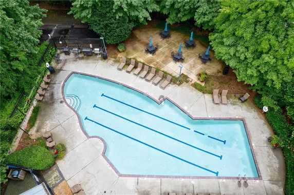 Aerial view of an outdoor swimming pool with surrounding lounge chairs and umbrellas.