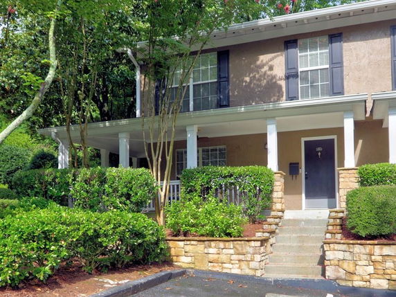 Front view of a two-story house with a covered porch and brick steps.