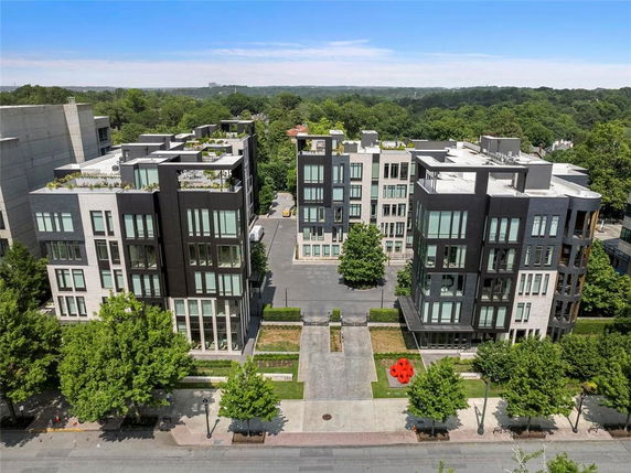 Aerial view of modern apartment buildings surrounded by trees with a view of the distant landscape.