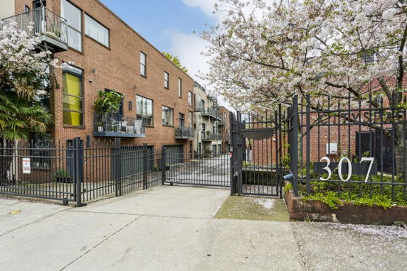 Front view of a multi-story brick building with gated entrance.