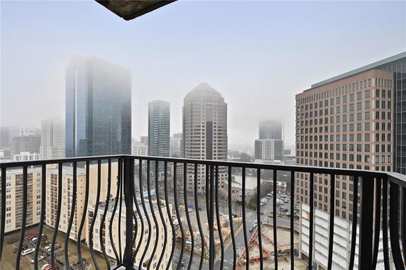 Panoramic view from a balcony overlooking tall buildings in a foggy cityscape.