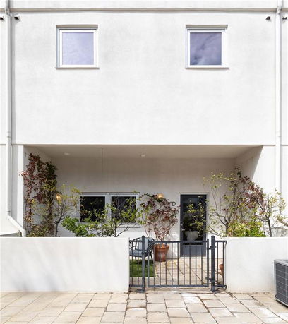 Front view of a two-story house with a gated entrance and patio area.
