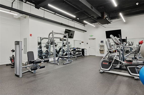 Indoor gym area with fitness equipment including exercise bikes, weight machines, and treadmills.