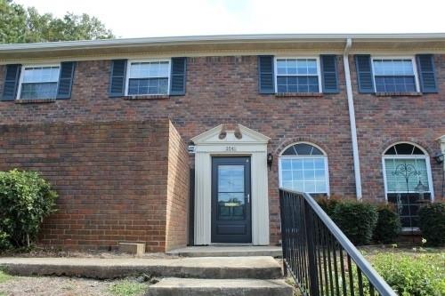 Front view of a two-story brick building with a black door and white trim.