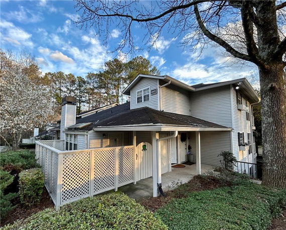 Front view of a two-story house with a covered entry and lattice fence.
