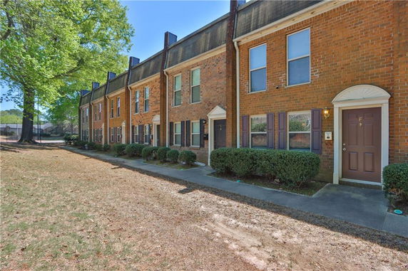 Front view of a brick row house with multiple units and a shared walkway.