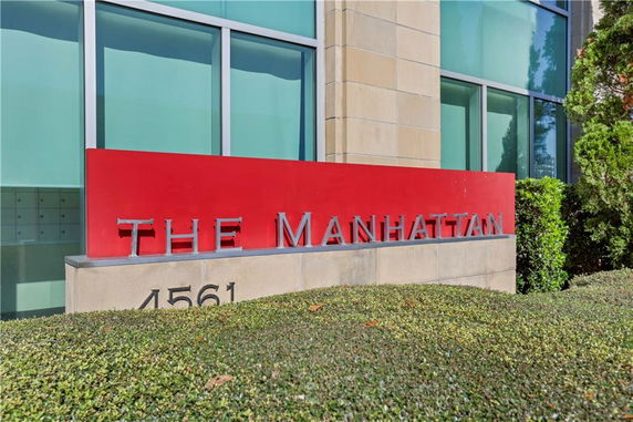 Front view of a building with large windows and a red sign reading 'The Manhattan'.