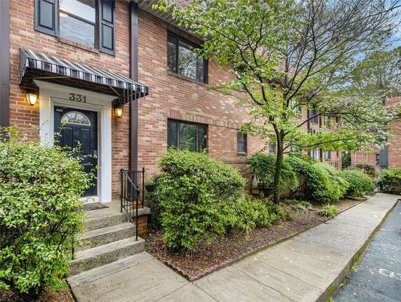 Front view of a brick townhouse with a black door and striped awning.