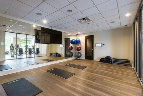 Room with exercise mats, exercise balls, and a wall-mounted monitor.