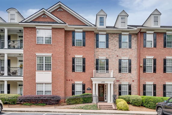 Front view of a multi-story brick apartment building with multiple windows and entry doors.
