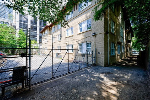 Front view of a multi-story brick building with a gated entrance.