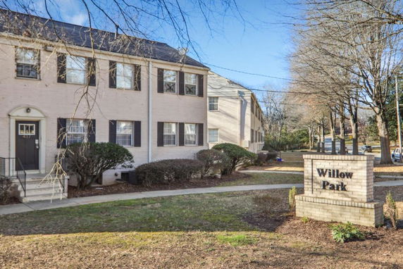 Front view of a two-story brick apartment building with multiple windows and a sign reading 'Willow Park'.