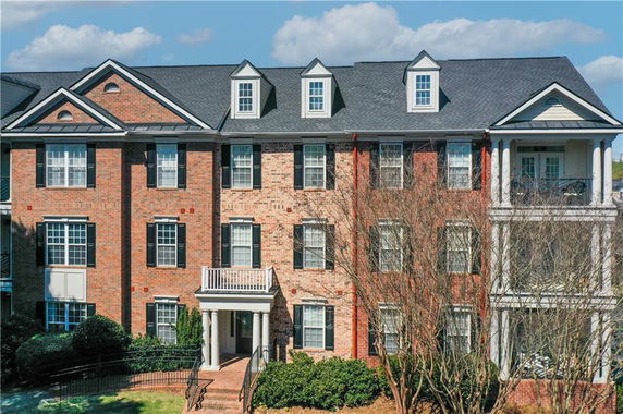 Front view of a three-story brick building with dormer windows and a small balcony.