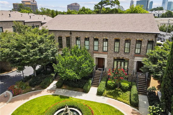 Front view of a two-story brick building with multiple entrances and windows, surrounded by greenery.