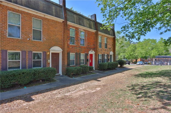 Front view of a two-story brick townhouse with multiple entrances and windows.