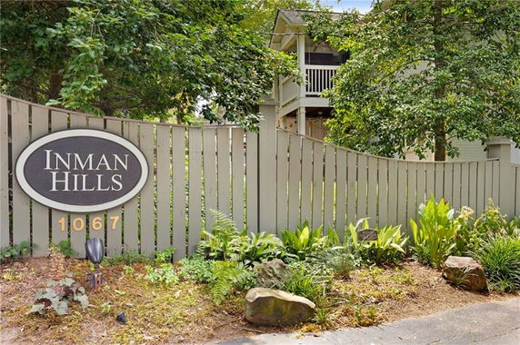 Front view of a residential building with a beige fence and a sign reading 'Inman Hills 1067'.
