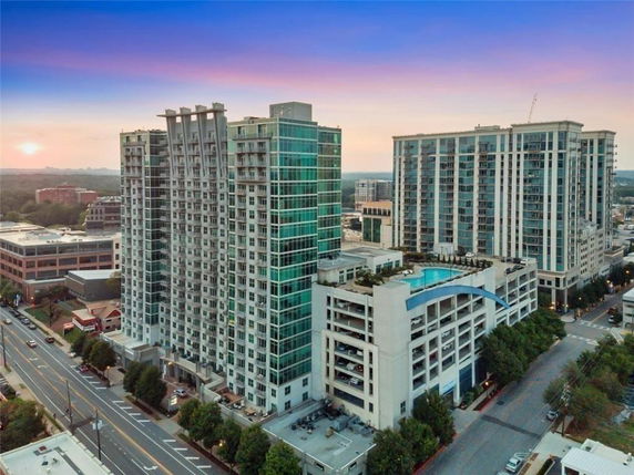 Front view of a multi-story residential building with a rooftop pool and attached parking structure.