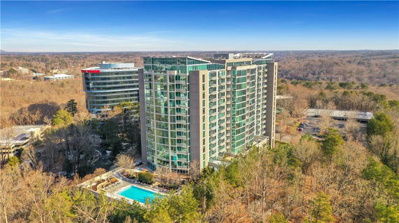 Front view of a modern multi-story building in a wooded area.