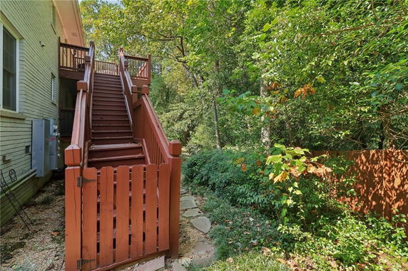 Side view of a house with an exterior staircase leading to an upper deck.