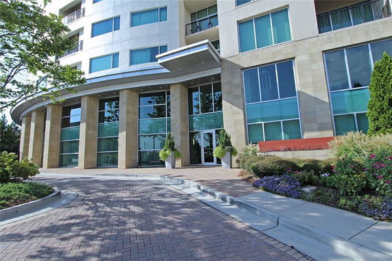 Front view of a modern multi-story building with large glass windows and stone columns.