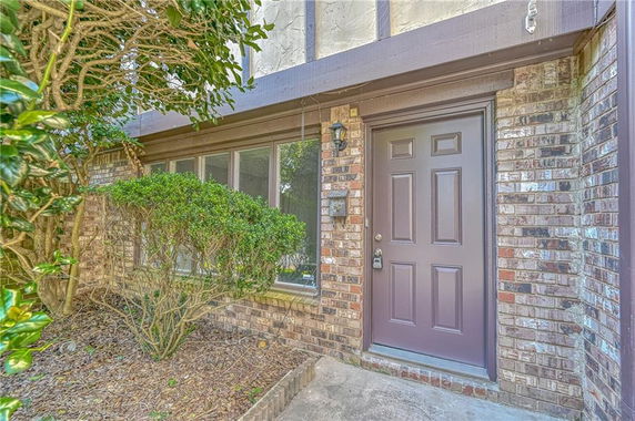 Front view of a house with a brick exterior and a brown front door.