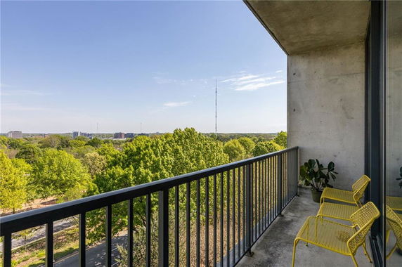 Balcony view overlooking a green landscape with distant buildings.