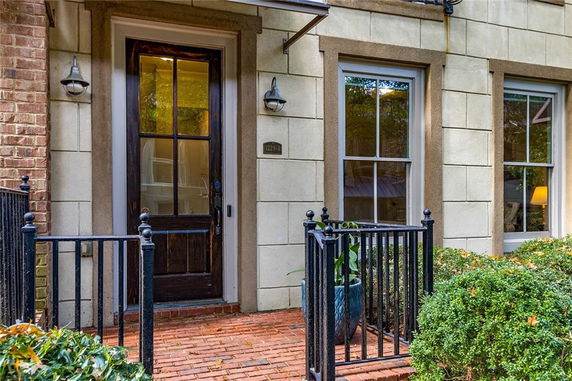 Front view of a house entrance with a wooden door and brick walkway.