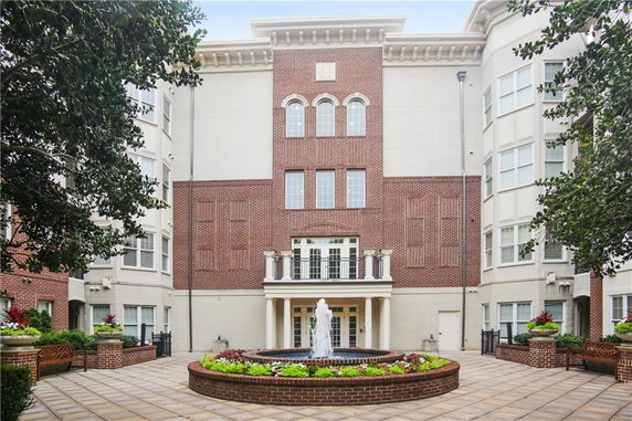 Front view of a multi-story building with brick facade and central fountain.