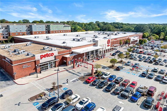 Aerial view of a commercial building with multiple storefronts including Petco and Target, surrounded by a large parking area.