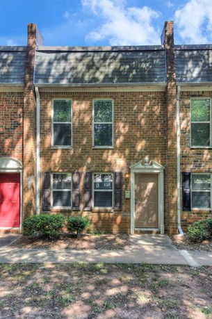 Front view of a two-story brick townhouse with a flat roof and a central door.