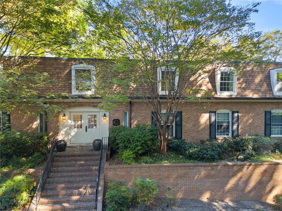 Front view of a two-story brick house with dormer windows and a central entrance.