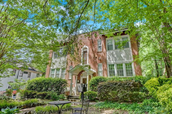 Front view of a two-story brick house with large windows and a small porch.