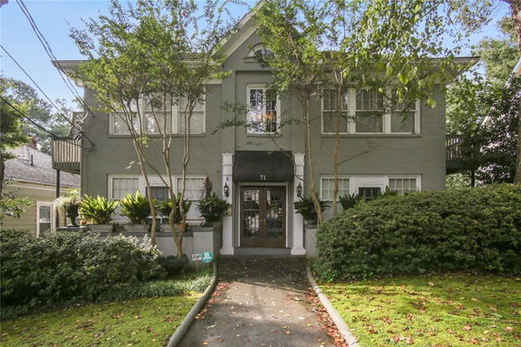 Front view of a two-story house with an arched entrance and greenery.