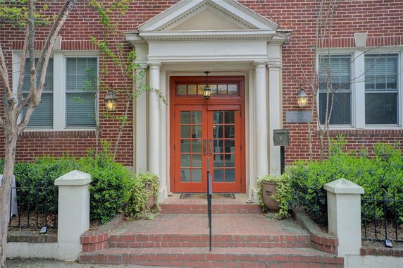 Front view of a brick building entrance with stairs and double doors.