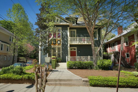 Front view of a multi-story house with a porch and balcony.