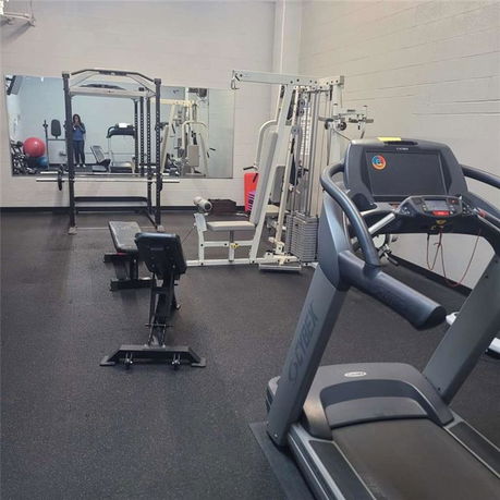 Indoor gym area with exercise equipment including a treadmill, bench, and weight machine.