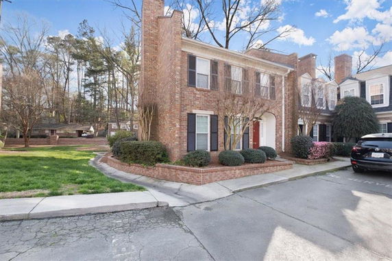 Front view of a two-story brick townhouse with red door and shingled roof.