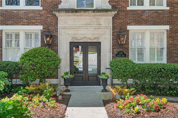 Front view of a brick building entrance with a glass door and surrounding landscaping.