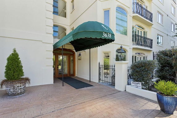 Front view of a multi-story building with a covered entrance and decorative railings.