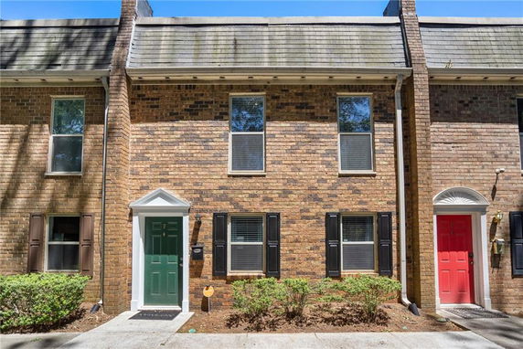 Front view of a townhouse with a green door and brick exterior.