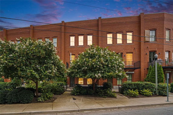 Front view of a multi-story brick building with large windows and balconies.