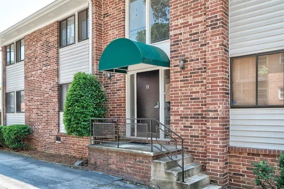 Front view of a brick building entrance with a green awning.