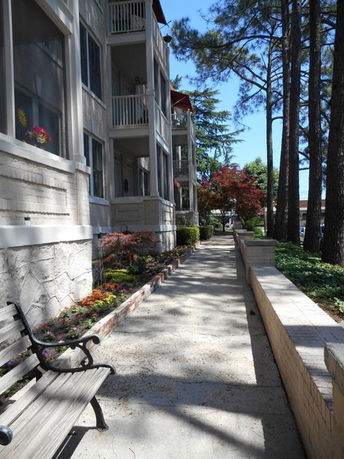 Side view of a multi-story building with balconies and a landscaped walkway.