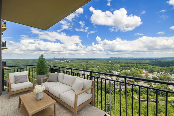 Balcony view overlooking lush green landscape and distant skyline.