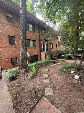 Front view of a multi-story brick building with windows and a small porch area.