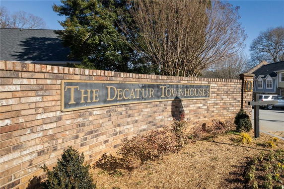 Front view of townhouse complex entrance with brick wall.