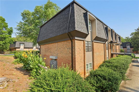 View of a multi-story brick building with dark shingle roofs and multiple windows.