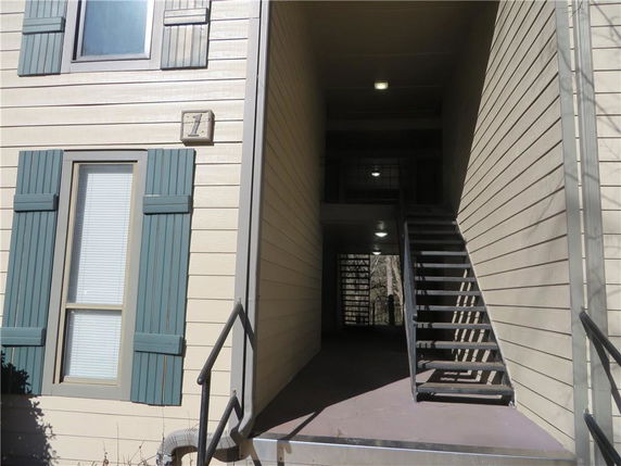Front view of a building with exterior stairs and windows with shutters.