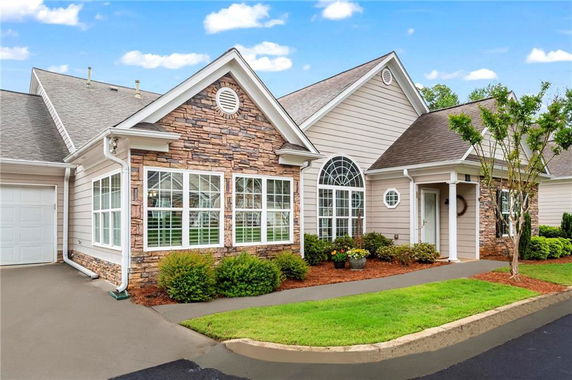 Front view of a house with stone accents and large windows.