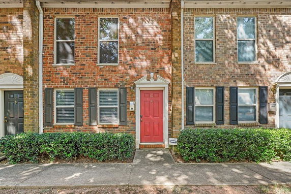Front view of a two-story townhouse with red brick exterior and a red door.
